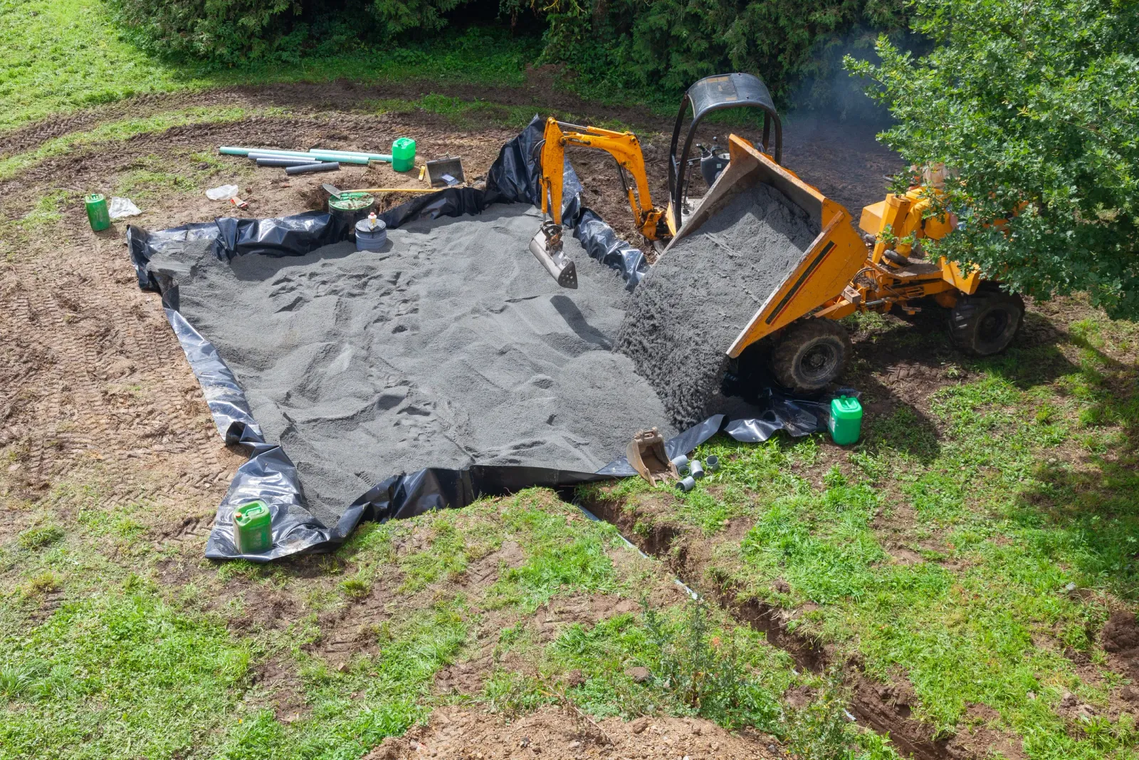 Excavation equipment installing a new septic system's filter bed at a property