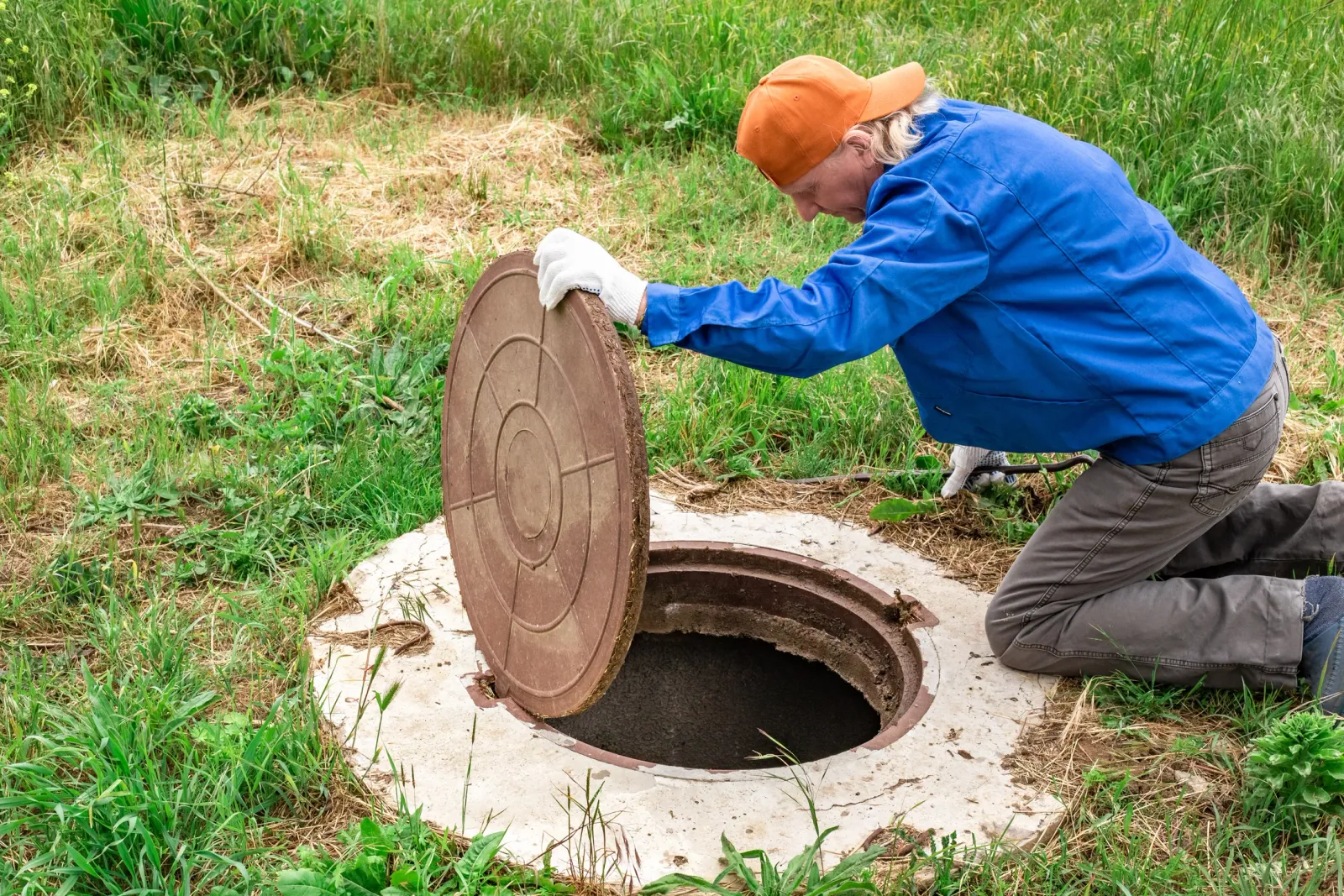 A septic tank access lid opened at a residential property ahead of a pumping service